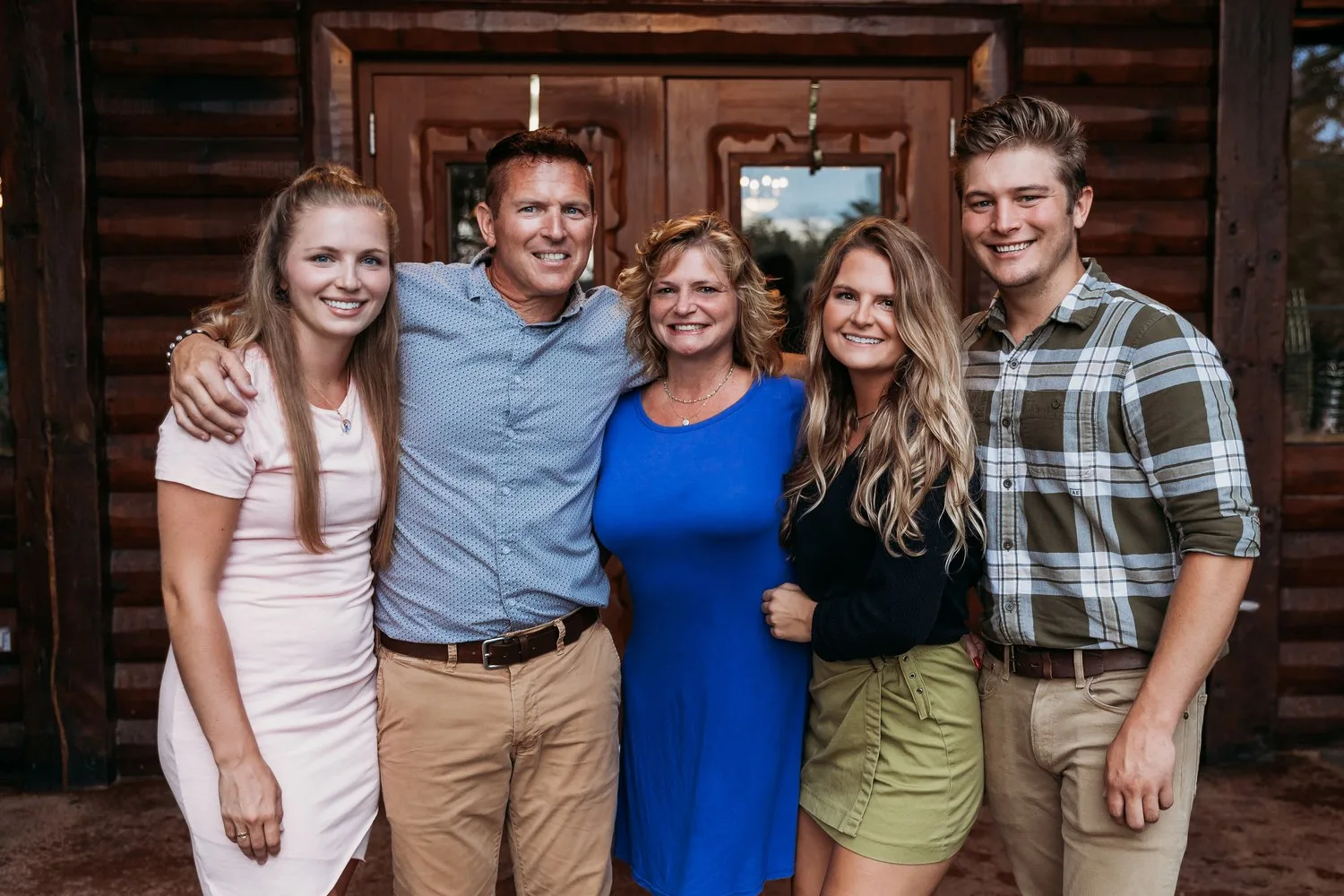 Brian and Holly Duffy with their three grown children outside a log home