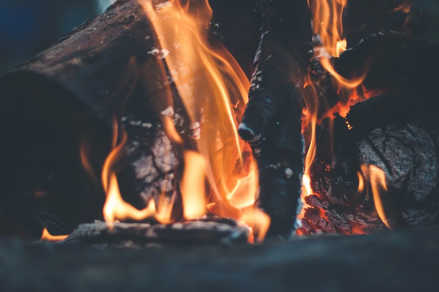 Firewood burning down, with glowing embers underneath the logs, from the shop's website