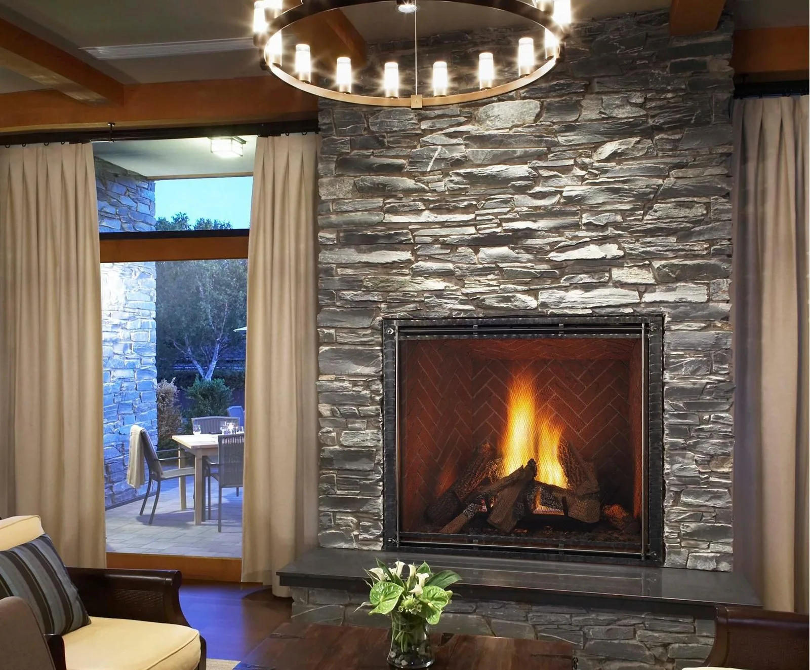 Stone fireplace with a timber mantel in a living room, from Northwoods Stove & Fireplace's website