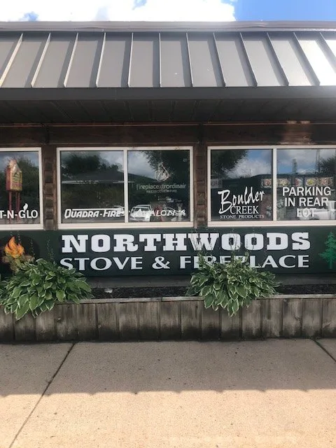 The Northwoods Stove & Fireplace log-sided storefront and green sign on Highway 63